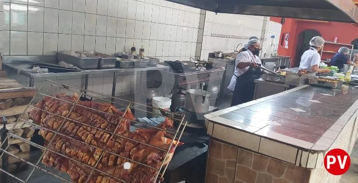 Cocina del restaurante campestre Warmy de Jaime y Nelly. 4 personas preparando las comidas y destaca el chancho en su parrilla.