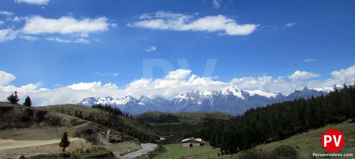 Una pequeña sobre el verde césped, a lado de una autopista y rodeado de montañas y necvados en Apurímac